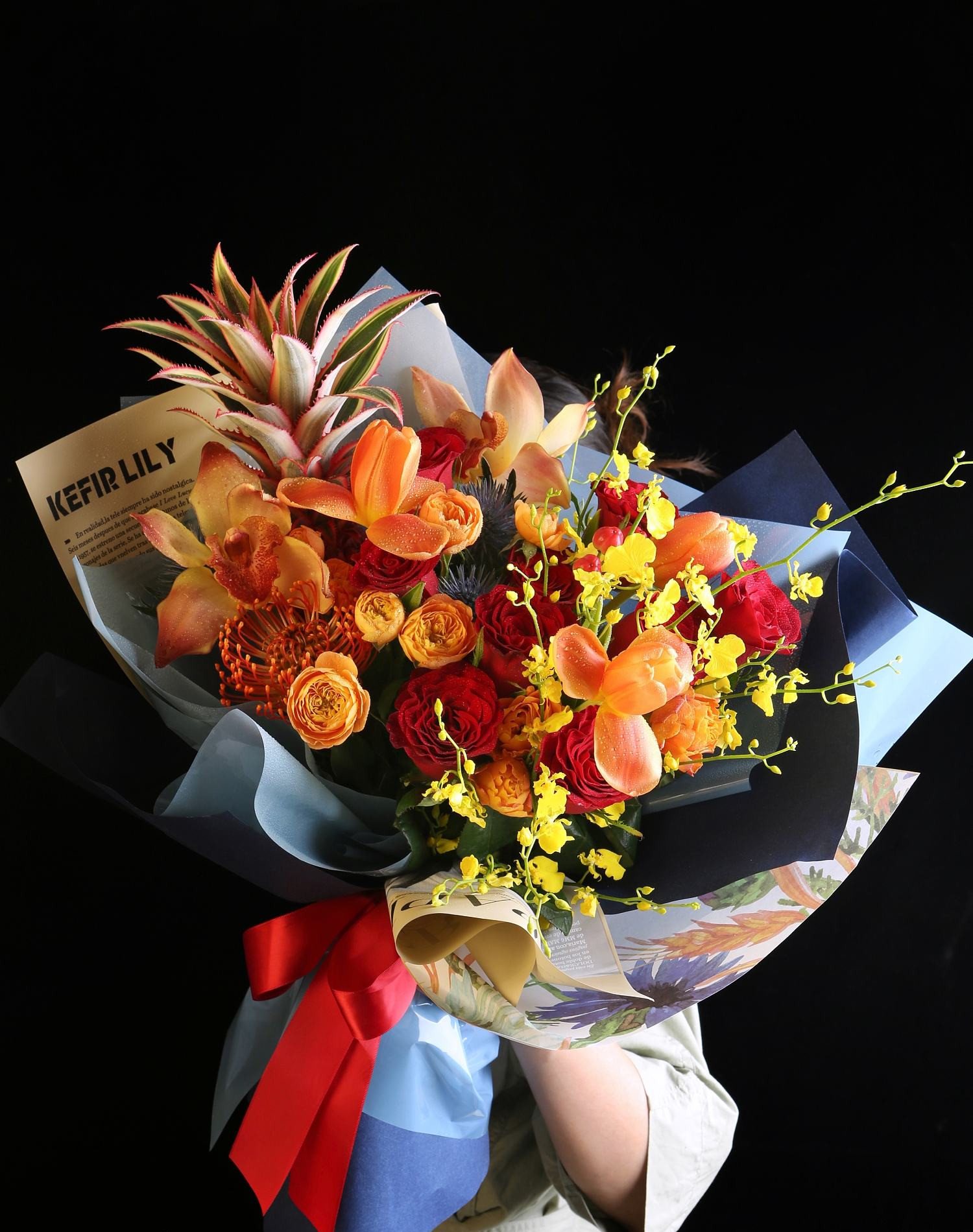 紅橙玫瑰、橙黃色蘭花與混合配花手綁花束